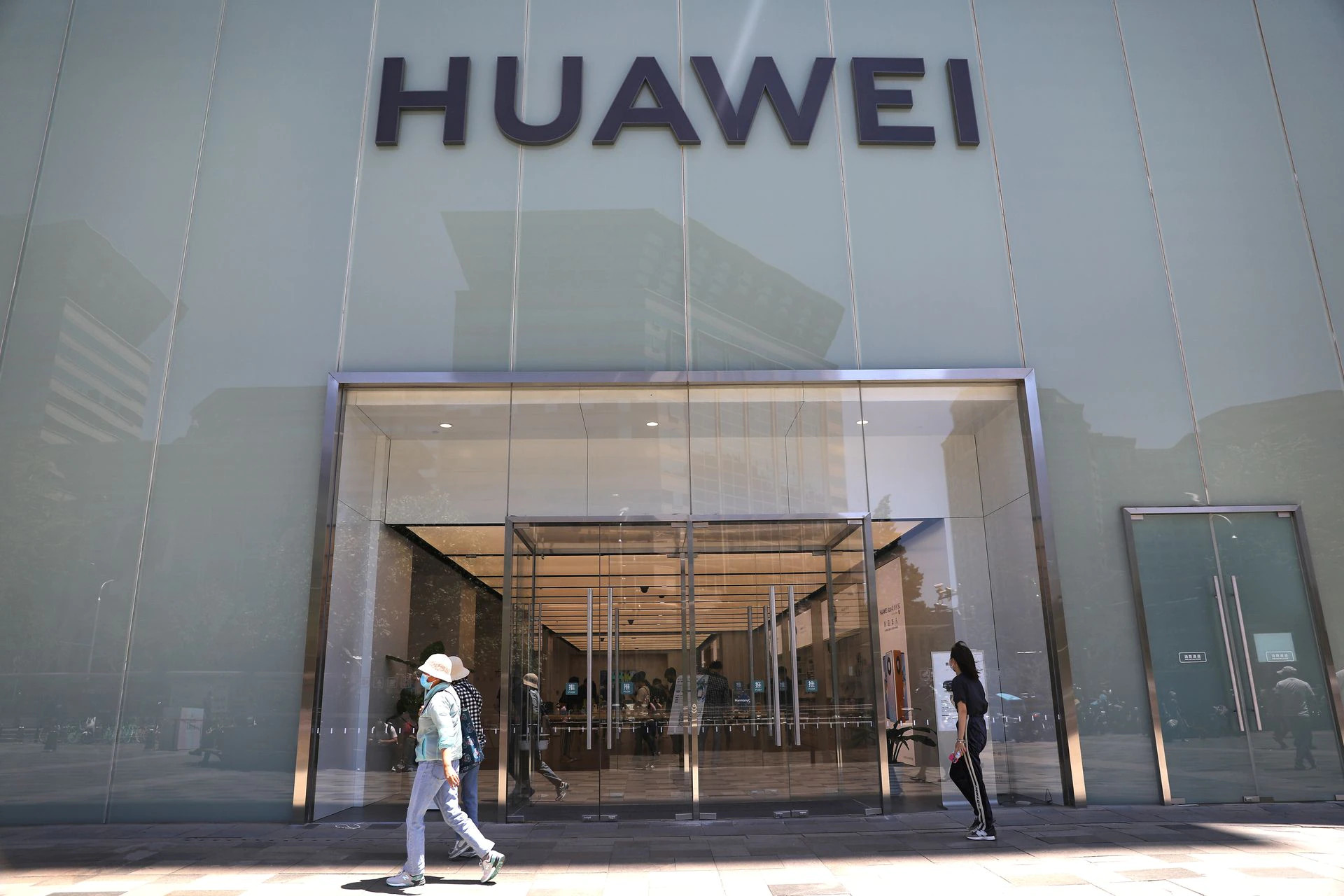 Gyalogosok egy pekingi Huawei kereskeds eltt (Kp Reuters/Tingshu Wang)